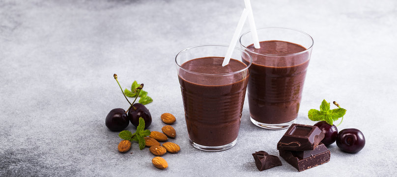 banner of Chocolate smoothies with cherries and almonds. on a table of gray stone. Vegan protein drink for athletes and gourmets