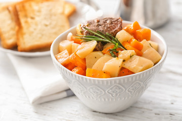 Bowl with tasty meat and potatoes on table