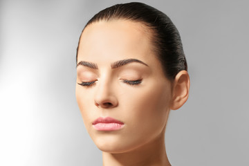 Naklejka premium Young woman with beautiful eyebrows on light background