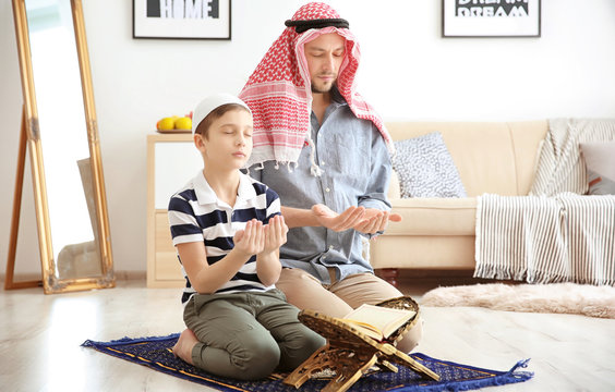 Muslim man praying with son at home