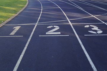 Start positions of a blue outdoor stadium running track with white dividing lines