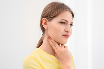 Young woman checking pulse on light background