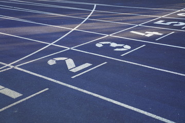 Start positions of a blue outdoor stadium running track with white dividing lines
