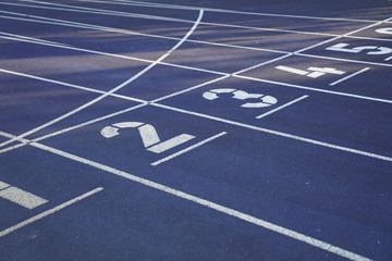 Start positions of a blue outdoor stadium running track with white dividing lines