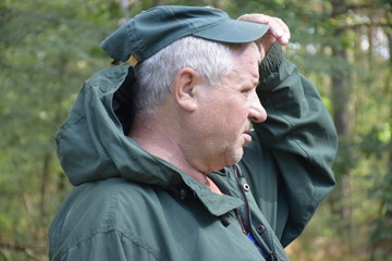 одетый кавказский старик,для защиты от насекомых,в лесу ищет грибы  