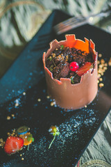 exclusive chocolate cake like tower with fruits served on black plate, product photography for patisserie, dessert for castle 