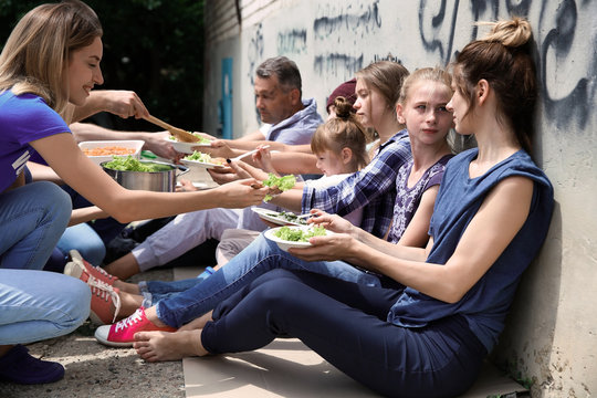 Poor people receiving food from volunteers outdoors