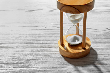 Hourglass with flowing sand on light wooden background. Time management