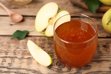 Glass of honey and apples on wooden table