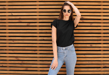 Young woman wearing black t-shirt against wooden wall on street. Urban style