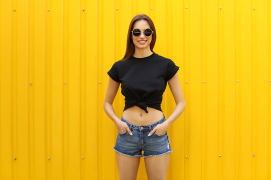 Young Woman Wearing Black T-shirt Near Color Wall On Street