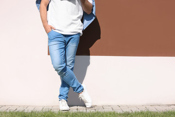 Fototapeta na wymiar Young hipster man in stylish jeans posing near color wall