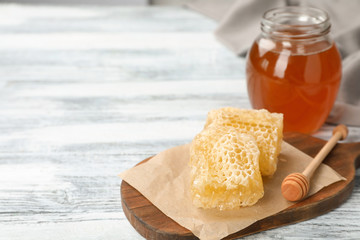 Composition with tasty fresh honeycombs and dipper on wooden board