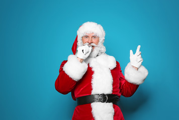 Fototapeta na wymiar Santa Claus singing into microphone on color background. Christmas music