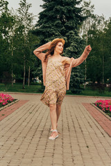 A romantic girl in the city wearing a dress and a sweater of warm colors, her hair develops in the...