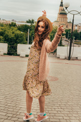 A romantic girl in the city wearing a dress and a sweater of warm colors, her hair develops in the...