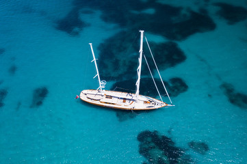 Aerial view of some yachts and a big sailboat on an emerald and transparent Mediterranean sea. Gulf of the Great Pevero,Sardinia, Italy.