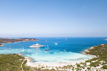Aerial view of an emerald and transparent mediterranean sea with a white beach and some yachts. Gulf of the Great Pevero,Sardinia, Italy.