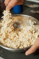 A man stirs ingredients in a metal bowl to make pastry dough.  The process of making apple pie.  Vertical image with shallow depth of field.