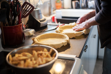 A man making homemade apple pies.  The process of making apple pies in a kitchen.  Vertical image with shallow depth of field.