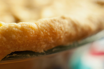 Close detail image of baked pie crust at the edge of an apple pie.  Horizontal with shallow depth of field.