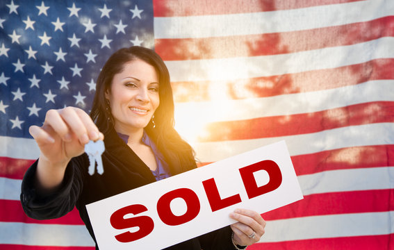 Hispanic Woman House Keys and Sold Sign In Front of American Flag