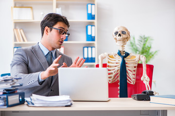 Businessman working with skeleton in office