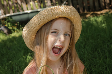 little girl growls in a straw hat in the summer