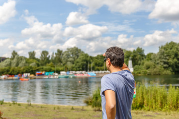 Fototapeta premium A man in a blue shirt can see something from one of the banks of a river in a beautiful day