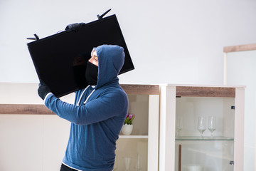 Man burglar stealing tv set from house