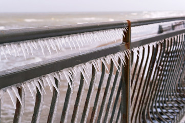 Icy iron fence. Metal fence covered with icicles.
