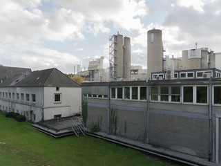 Fototapeta na wymiar A large gray factory with green trees and lawn in the autumn in clear weather