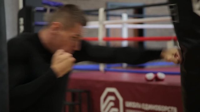 Strong man boxing using punch sake in gym, sunlight, close-up.