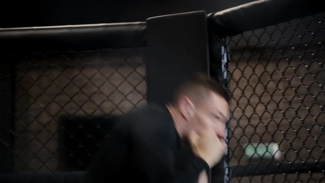 muscular fighter boxing in a black cage at gym.