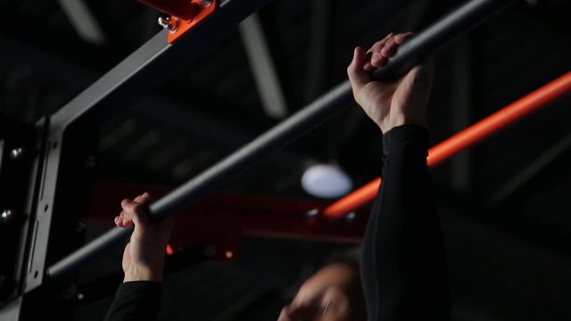 Man doing pull-ups in gym, black background, close-up