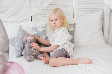 Girl in a beautiful outfit is lying on the bed with a plush cat