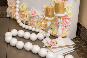 Romantic and gentle photozone for pastel pink wedding with candles, candlesticks and light tulle