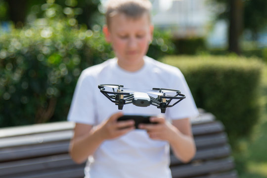A teenager boy starts a quadrocopter from a smartphone and takes a nature shoot for his video blog. Flying robot drone. Robotics and programming. STEM education. - Powered by Adobe