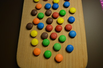 Matte beautiful sweets, shivering candies of brown, blue, orange, yellow and red on a wooden...