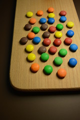 Matte beautiful sweets, shivering candies of brown, blue, orange, yellow and red on a wooden...