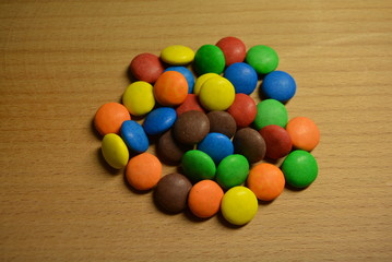 Matte beautiful sweets, shivering candies of brown, blue, orange, yellow and red on a wooden background