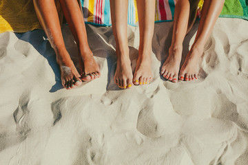 Close up of legs of three women at the beach - Powered by Adobe