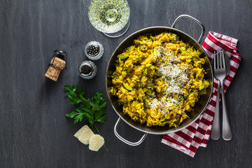 Italian dish yellow Risotto milanese with saffron, zucchini and Parmesan cheese on a black slate...