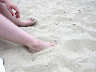 Woman sitting on the beach with her feet in the sand 