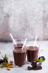 Black forest smoothies on the gray surface of the table. chocolate milk shake with nuts and cherries