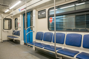 View of bright empty interior of modern subway train car. Contemporary inside space of the underground railway carriage with no one inside, empty seats.