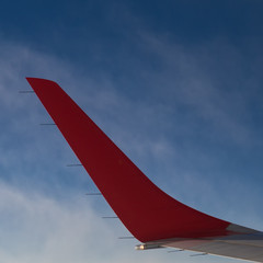 Aile d'avion rouge sur ciel bleu depuis les airs