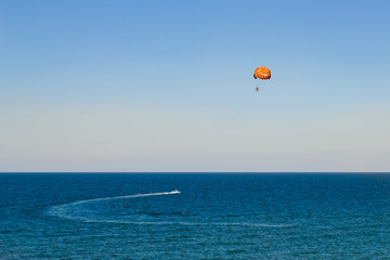 Three people are gliding using a parachute on the background of the blue sky. Copy space. Beach entertainment concept.