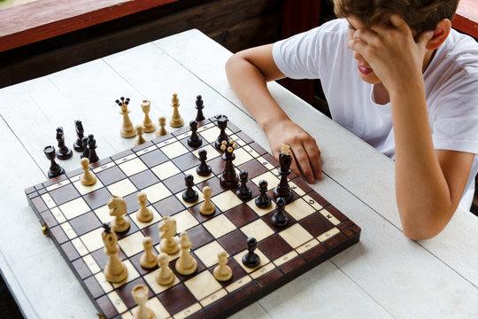 cute, smart, young boy  plays chess on the chessboard . Chess tournament, camp, training concept