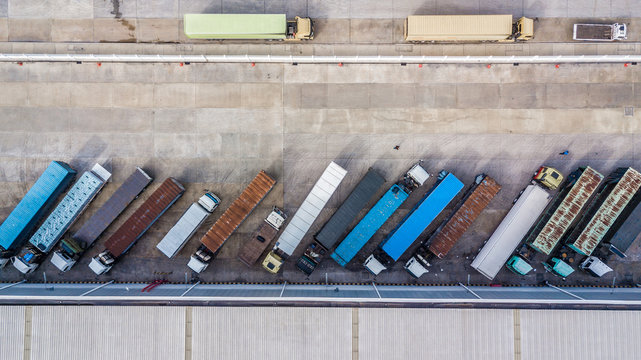 Aerial top view of truck and cargo trailer unloading in logostics center.
